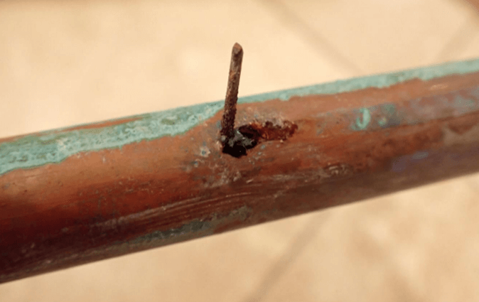 Careless construction work can result in plumbing leaks that go unnoticed until later, such as this nail driven through a pipe installed in a bathroom cabinet.