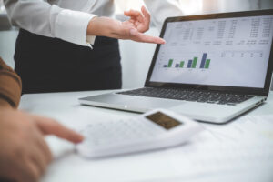 A businessman and woman focused on a laptop, reviewing graphs and statistics together in a professional setting.