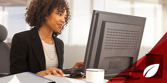 A woman seated at a desk, focused on her computer screen while typing.