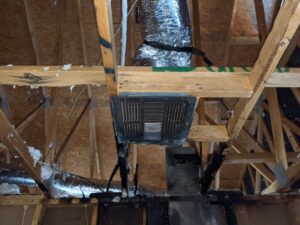 Exposed attic framing and ductwork with visible fire damage