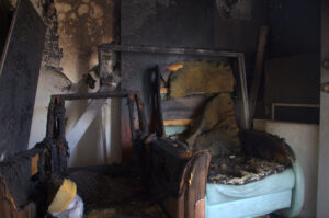 Fire-damaged room with heavily burned furniture and walls