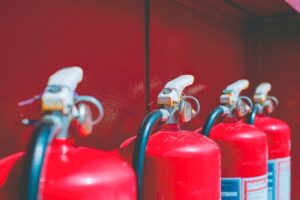 Four red fire extinguishers lined up against a red wall